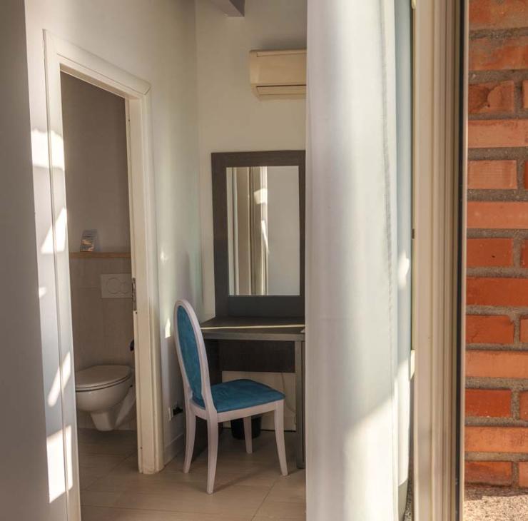 Meerblick von einem hellen Zimmer mit Terrasse und Sonnenschirmen.
